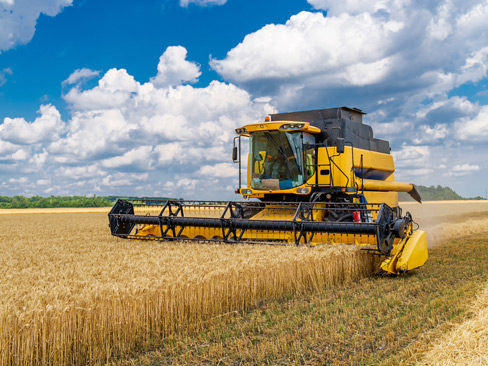 Great combine harvester working at the field. Agricultural machine on the blue sky.