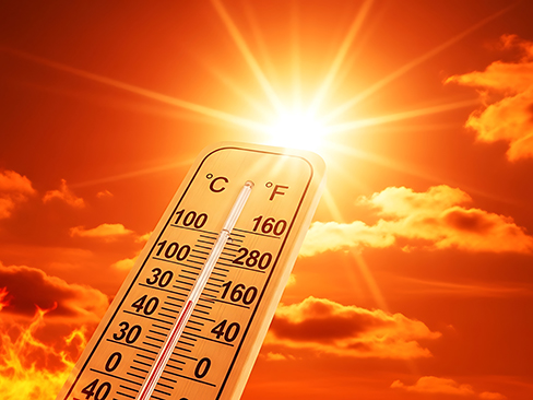 Thermometer showing high temperature against sunny sky with clouds