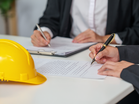 Cropped hands of business partners signing legal contract document in office